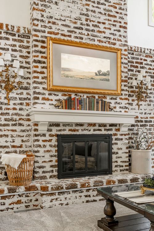 Brick fireplace with a gilt-framed landscape painting and mantel styled with books
