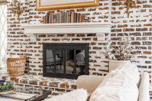 Close view of a brick fireplace mantel with stacked books and a woven basket