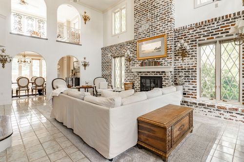 Living room with brick fireplace, slipcovered sofa and archways into a formal foyer