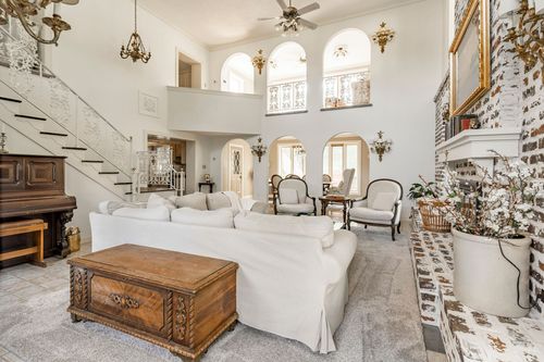 Living room with a curved staircase, upright piano and a carved wood storage trunk