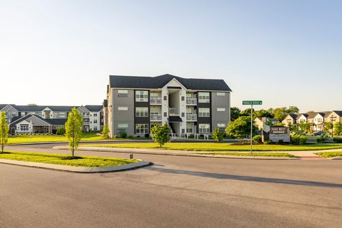 Three-story apartment building exterior at golden hour with entry sign and street view