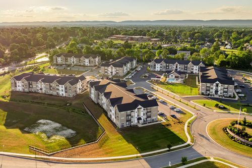 Aerial view of the apartment complex with a pond and distant mountains at dusk