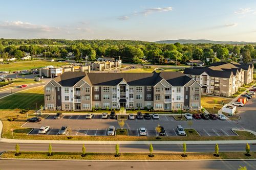 Aerial view of a single apartment building with parking and mountain views at dusk