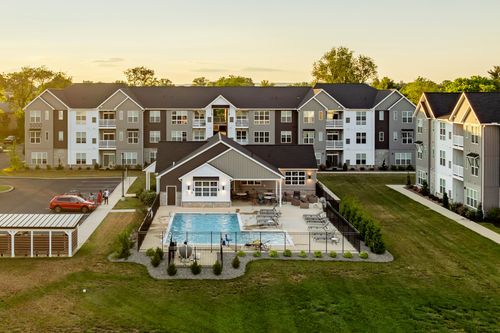 Aerial dusk view of an apartment complex with a resort-style pool and clubhouse