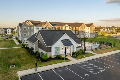 Aerial view of an apartment clubhouse entrance with a landscaped walkway at dusk