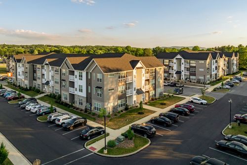 Aerial dusk view of a sprawling apartment complex surrounded by tree-lined parking lots