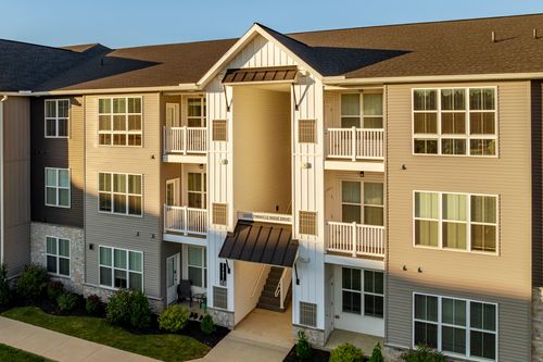 Close-up of a tan and gray apartment building with a covered breezeway entrance and balconies