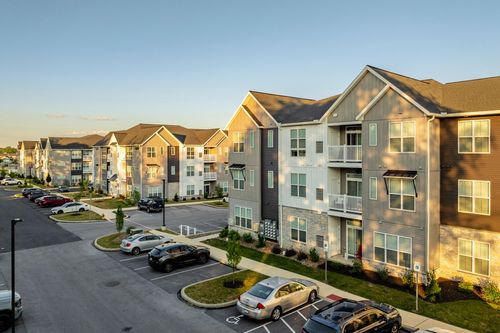 Aerial dusk view of apartment buildings with balconies bordering a parking lot