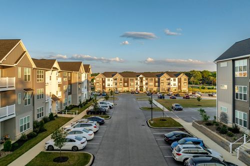 Aerial dusk view of an apartment courtyard flanked by residential buildings and parking