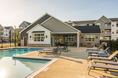 Clubhouse exterior with a covered patio overlooking the pool at dusk