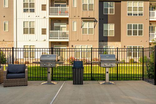 Fenced patio grilling station with two gas grills beside the apartment building
