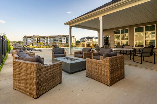 Covered patio with wicker lounge seating and a fire pit table by the pool