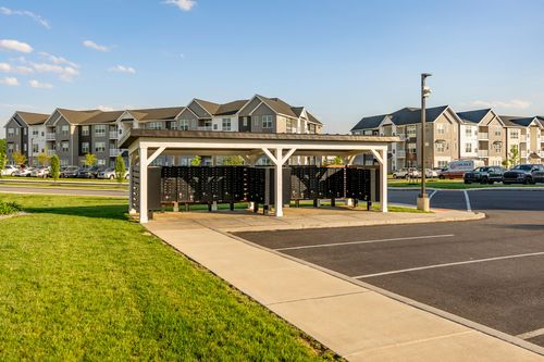 Mail kiosk pavilion with cluster mailboxes framed by apartment buildings