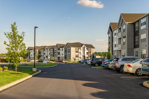 Street view of an apartment complex with parked cars and a streetlight at dusk