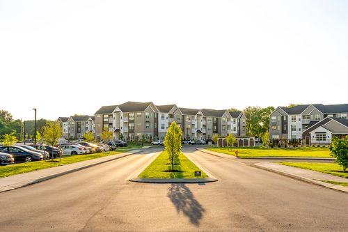 Street view of multiple apartment buildings at golden hour with parking areas