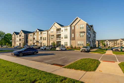 Apartment building exterior with a parked car and sidewalk in the foreground