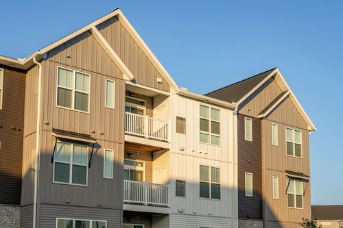 Close angle of a gable-roofed apartment building with mixed siding colors