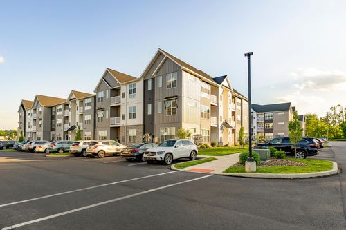 Apartment building exterior with a full parking lot at dusk