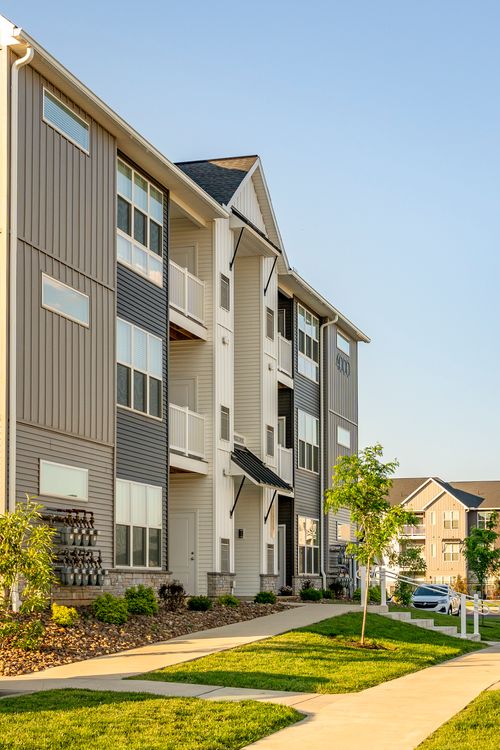 Angled apartment building exterior with string lights on a ground-floor patio