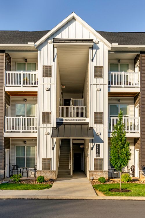 Apartment building entry with stairway signage and patio furniture below