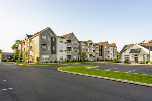 Apartment buildings around a circular drive with a clubhouse in the distance