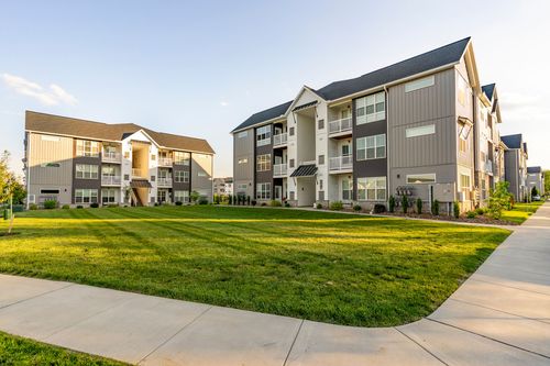 Apartment buildings across an open lawn with a sidewalk at dusk