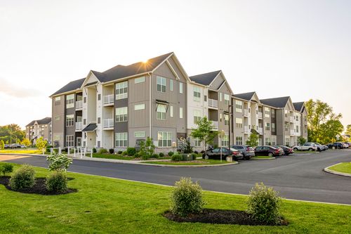 Wide exterior view of an apartment building with a full parking lot at golden hour