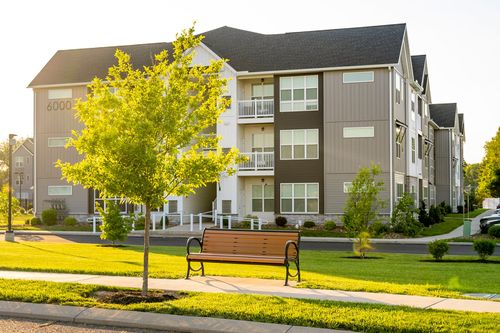 Apartment building exterior with a wooden bench set on the lawn
