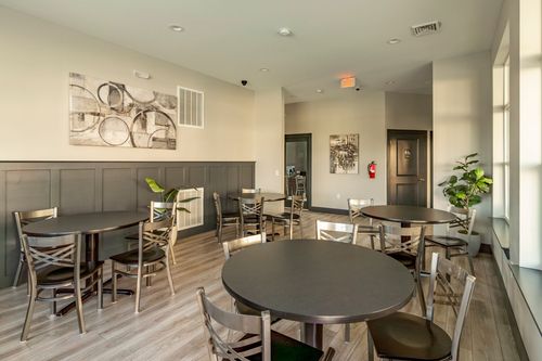 Community room with round tables, wood flooring and wall art