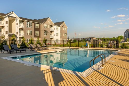 Outdoor pool with lounge chairs beside the apartment building at golden hour