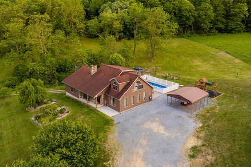 Aerial dusk view of a farmhouse with a pool overlooking rolling farmland and mountains
