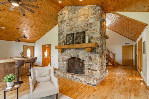 Floor-to-ceiling stone fireplace opening onto a hallway with a staircase