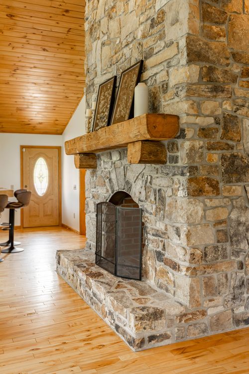 Stone fireplace mantel with candles and framed art beside the front entry