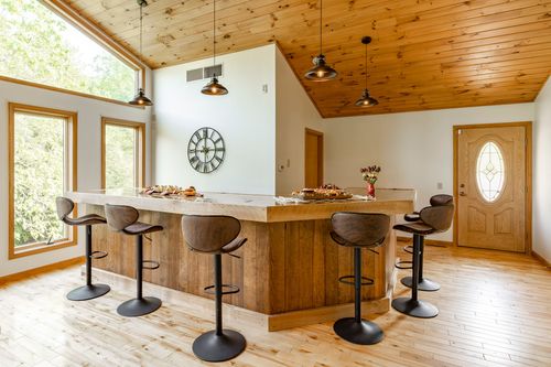 Kitchen island with leather bar stools, pendant lighting and a vaulted wood ceiling
