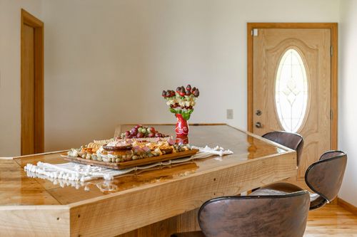 Wood table set with a charcuterie board, fruit and flowers near the entry