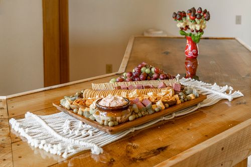 Charcuterie board with crackers, cheese and grapes on a macrame table runner