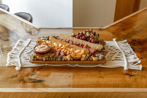 Charcuterie board loaded with crackers, meats, cheeses and grapes on a wood table