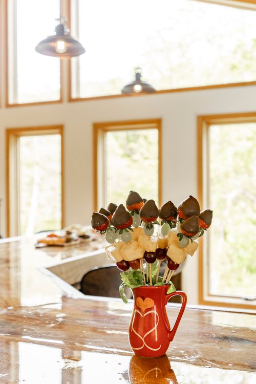 Chocolate-dipped strawberry and fruit skewers displayed in a heart-patterned pitcher