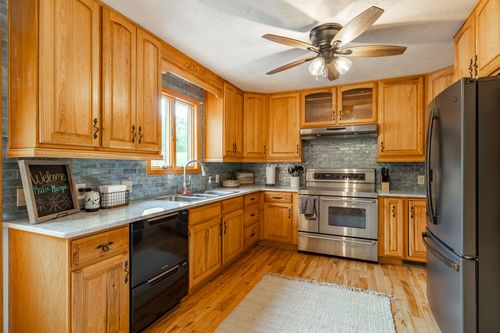 Kitchen with oak cabinets, granite counters and a stainless range beneath a ceiling fan
