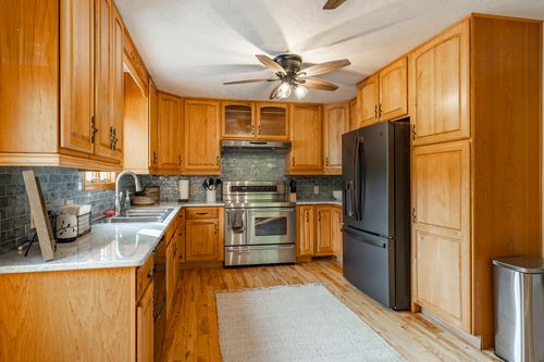 Kitchen with oak cabinetry, tile backsplash and a black stainless refrigerator