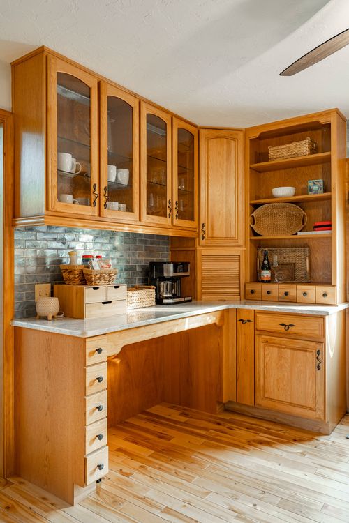 Kitchen coffee station with glass-front cabinets, wicker baskets and open shelving