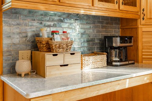 Coffee station with a drip coffee maker and woven baskets against a blue tile backsplash