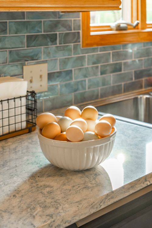 Bowl of fresh farm eggs in shades of brown, white and blue on a marble counter