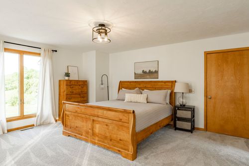 Bedroom with a wood sleigh bed, dresser and a bright window seating area