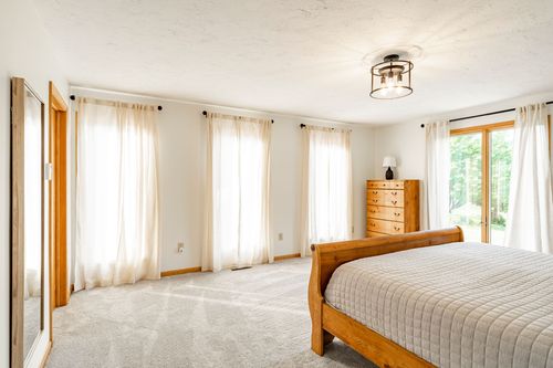 Bright bedroom with sheer curtains on multiple windows and a wood sleigh bed