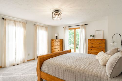 Bedroom with a wood sleigh bed, dresser and sliding glass doors to a deck
