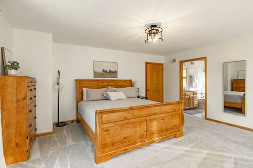 Bedroom with a wood sleigh bed, matching dresser and a view into an ensuite bathroom