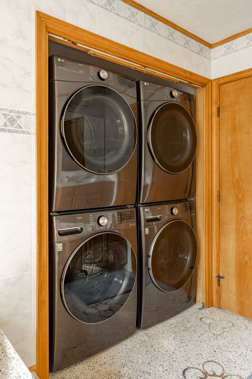 Stacked charcoal washer and dryer set within a wood-trimmed laundry nook