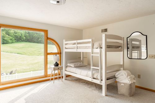 White twin-over-full bunk bed with a round mirror and a woven hamper nearby