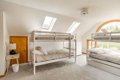 Bunk beds beside a nightstand lamp with skylights and views of rolling green hills